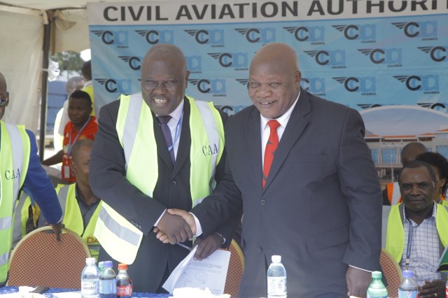 Aggrey Bagiire State Minister for Works and Transport in Uganda (L) shakes hands with Hon. Kamwelwe Isack Aloyce Minister of Transport in Tanzania (R) during the launch of Air Tanzania’s inaugural flight to Uganda on August 26th 2018 at Entebbe Airport. The 76-Seater Q400 series plane touched down at 13:01pm and was received by stakeholders, Civil Aviation Authority officials and Air Tanzania officials.