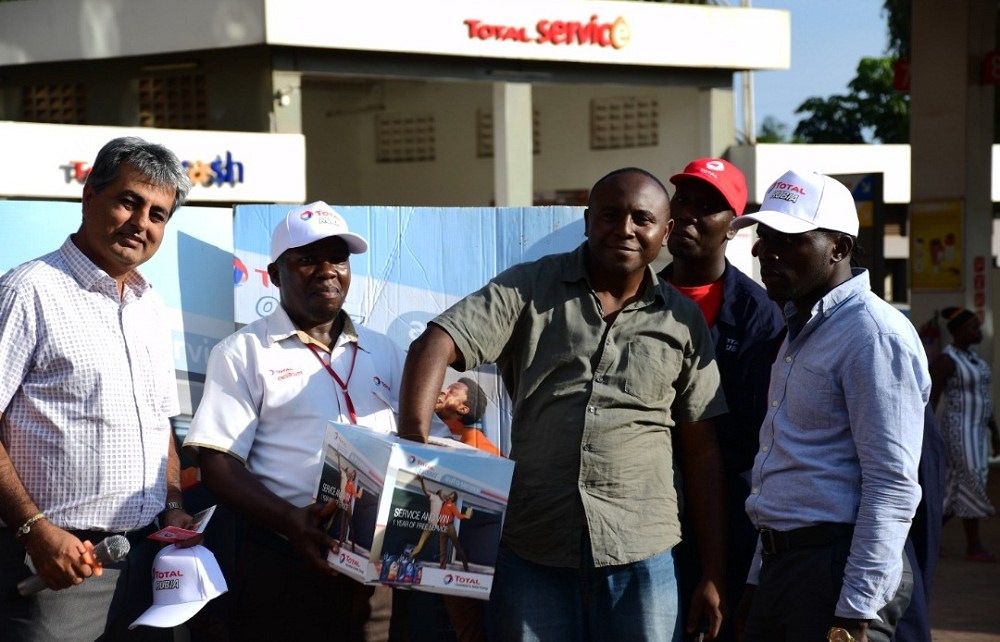Tushar Mashru (2nd L), Total Uganda dealer, Richard Jjuko, (C) Total Wampewo Station Manager, with a customer picking a raffle ticket during the Total Uganda “Extra Mile” promotion on 2nd November 2018 at Total Wampeewo station. Lucky Winners of the draw will get free full-year car service.