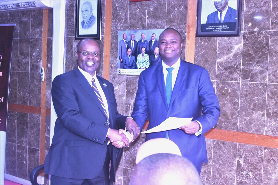 Deputy Governor, Dr. Louis Kasekende (right) hands Stanbic Bank CEO Patrick Mweheire the award