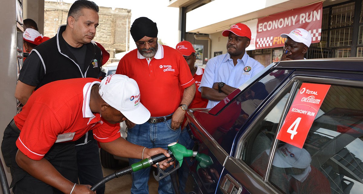 Micky Bassi (centre) watches Total Excellium Economy Run officials fill his Alfa 75 sports saloon at the finish of the 2018 event which he won. Bassi will defend his title this year on June 22nd.