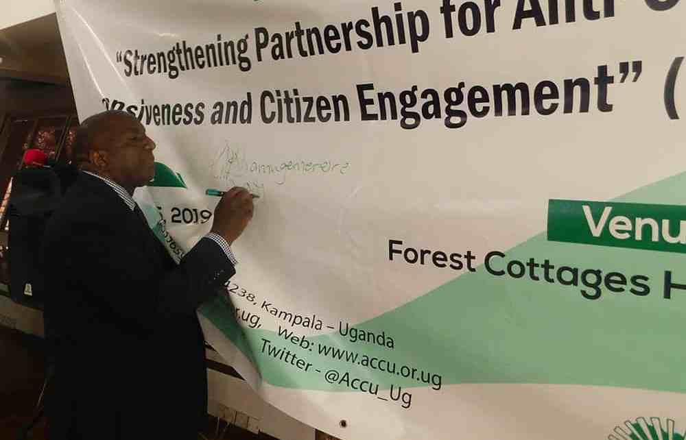 The Deputy Inspector General of Government George Bamugemereire signing on the project banner as sign of commitment to support the project